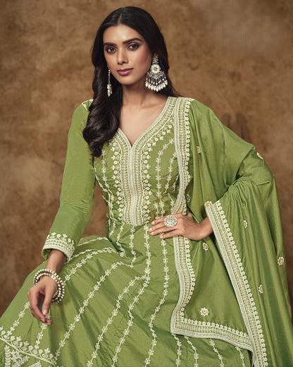 Woman wearing a green embroidered traditional outfit against a brown background