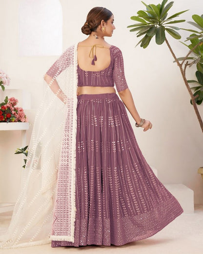 Woman wearing a purple traditional outfit with a white border indoors.