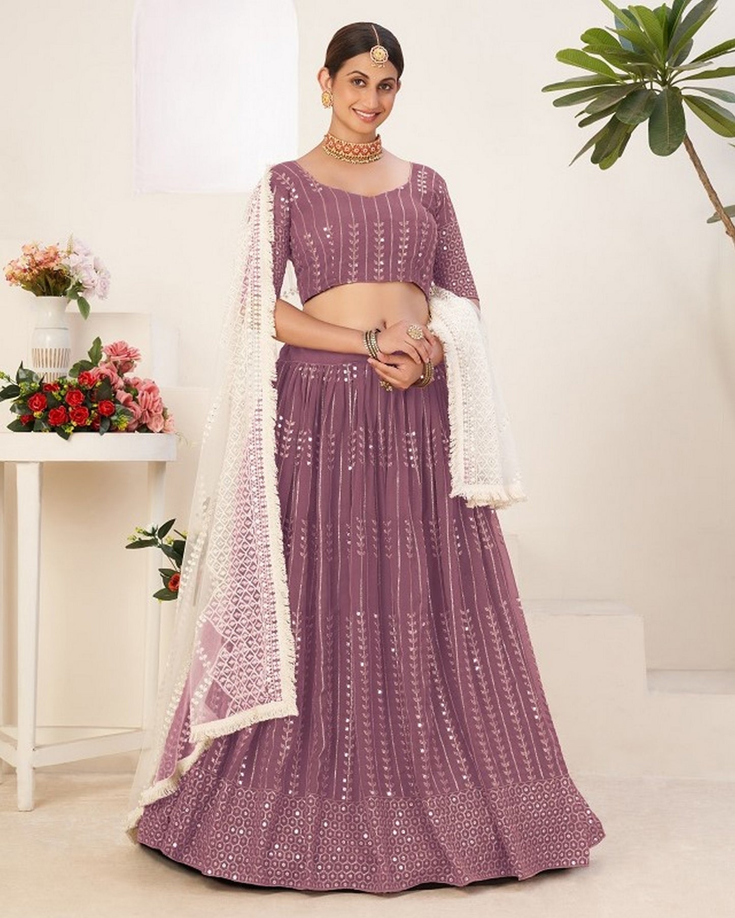 Woman in a purple traditional outfit with a white dupatta in a well-lit room.