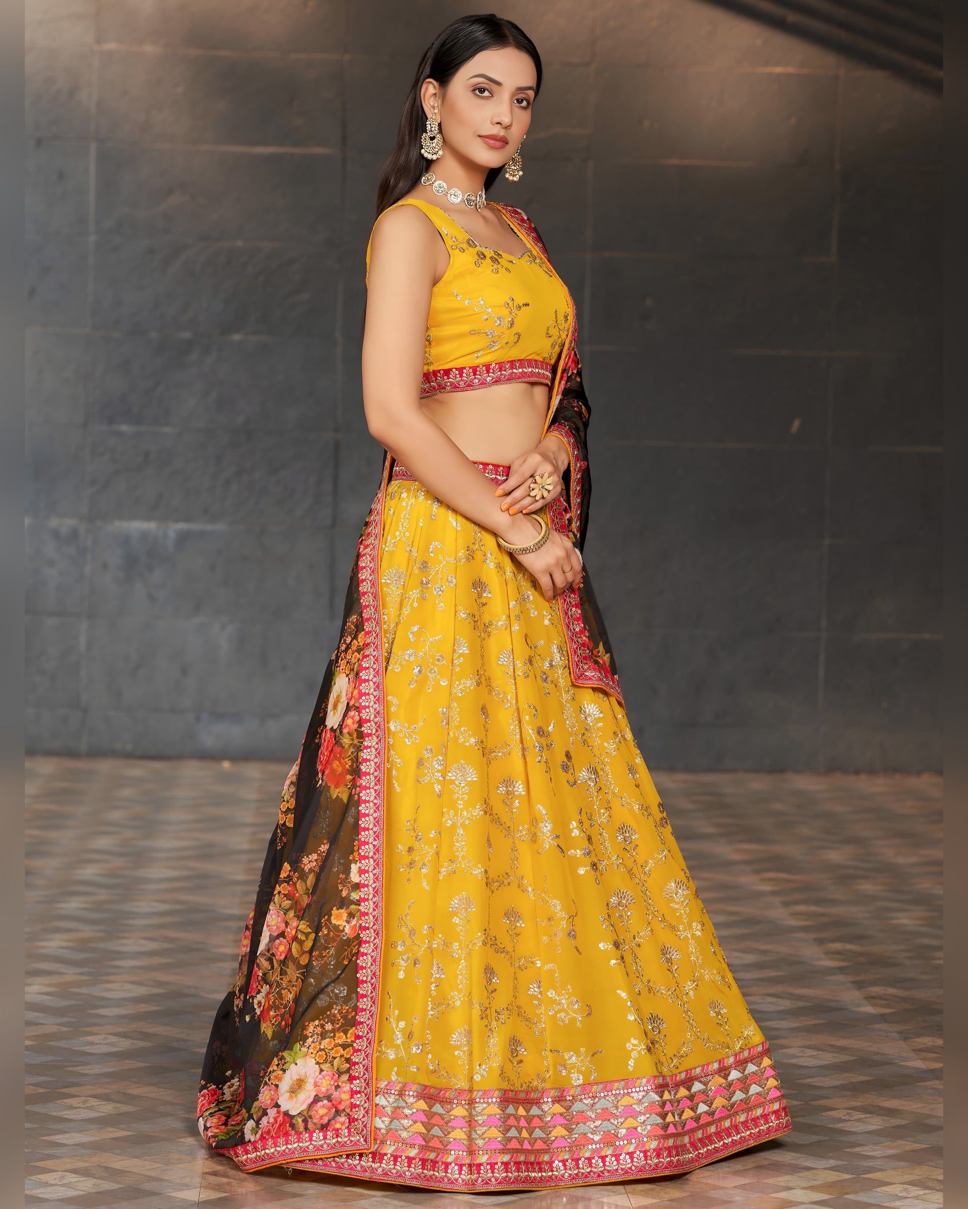 Woman wearing a yellow and black traditional outfit with floral patterns on a dark background