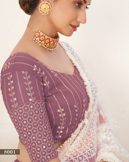 Woman wearing a purple blouse with white embroidery and gold jewelry on a beige background