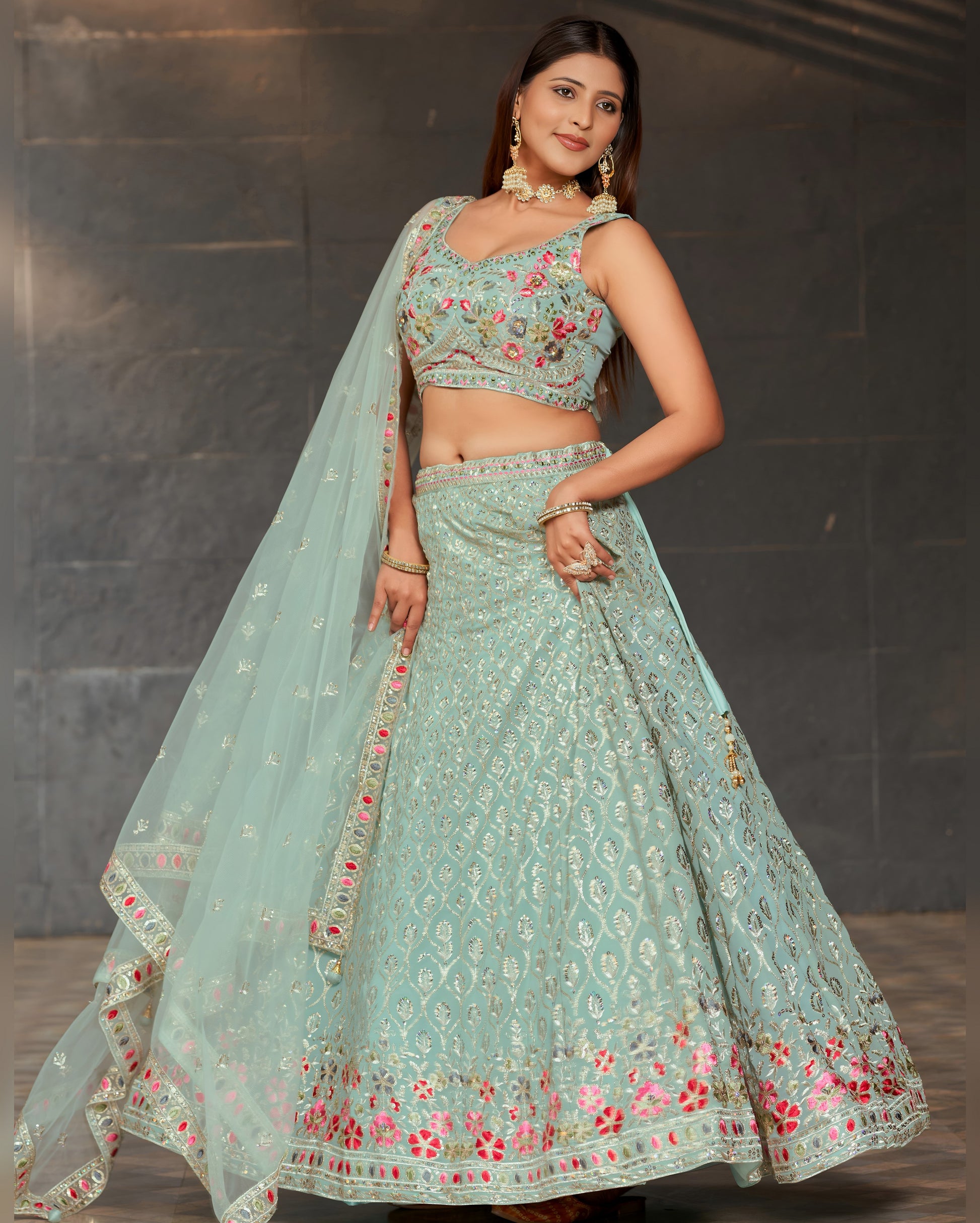 Woman wearing a light blue embroidered traditional outfit with a dark background