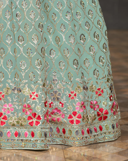 Light blue fabric with floral embroidery and sequins on a wooden floor.