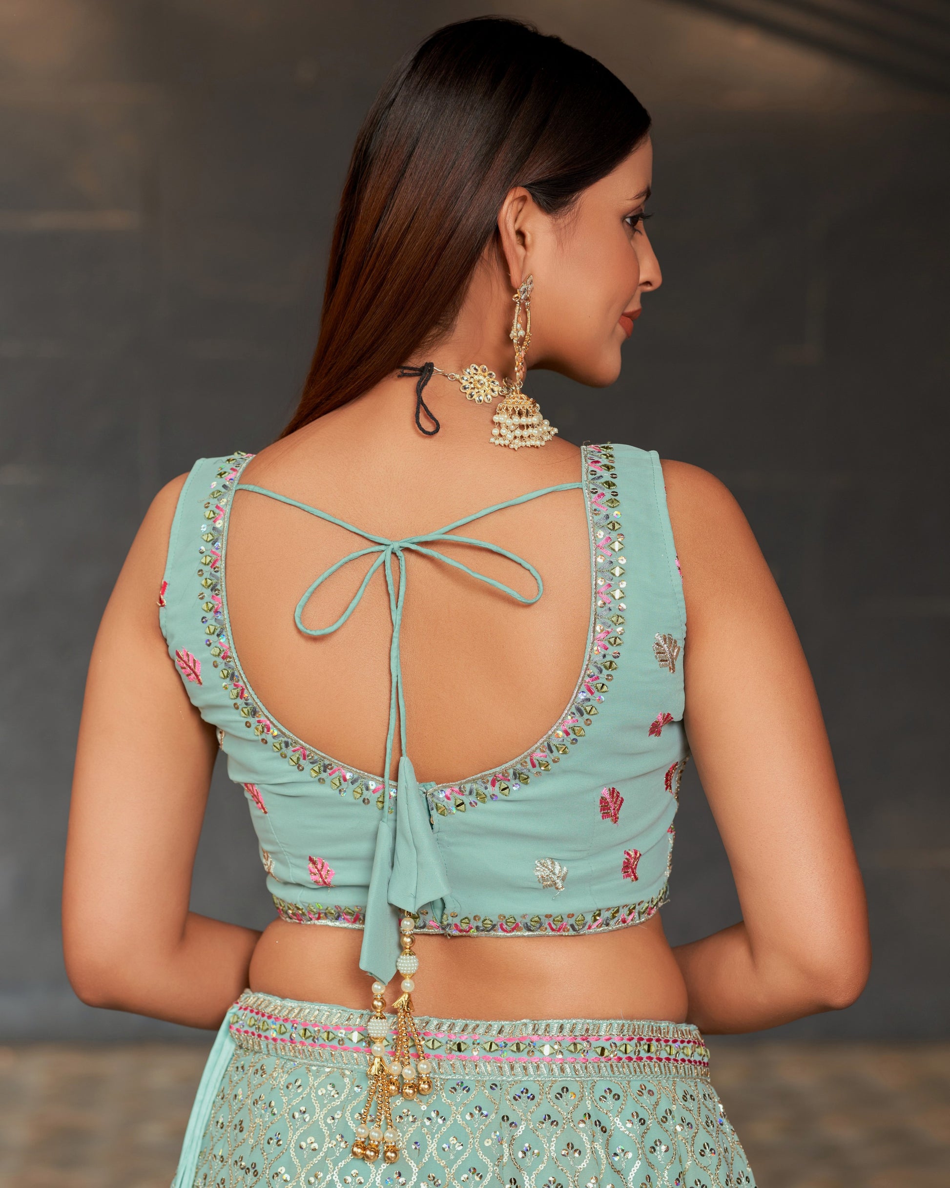 Woman wearing a light blue embroidered traditional outfit with a blurred background
