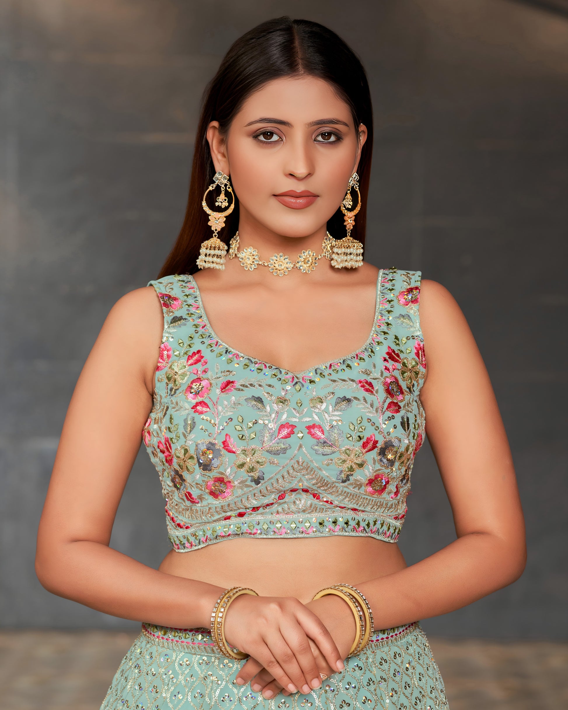 Woman wearing a traditional embroidered blouse with floral patterns against a neutral background