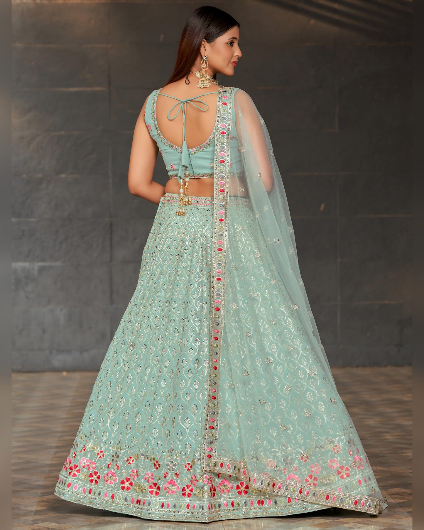 Woman wearing a light blue embroidered traditional outfit with a dark background