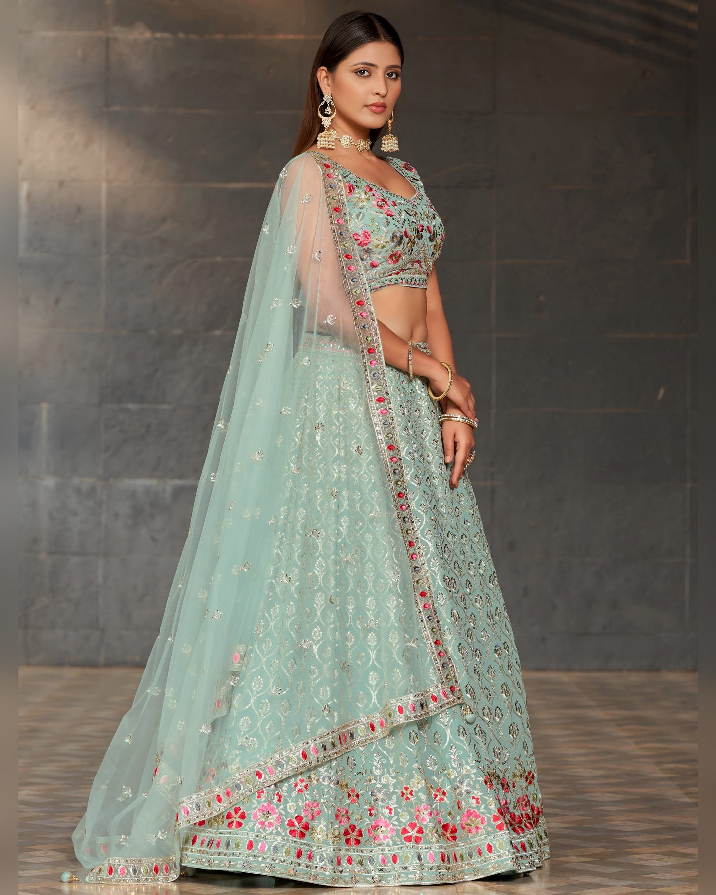 Woman wearing a light blue embroidered lehenga with a dark background