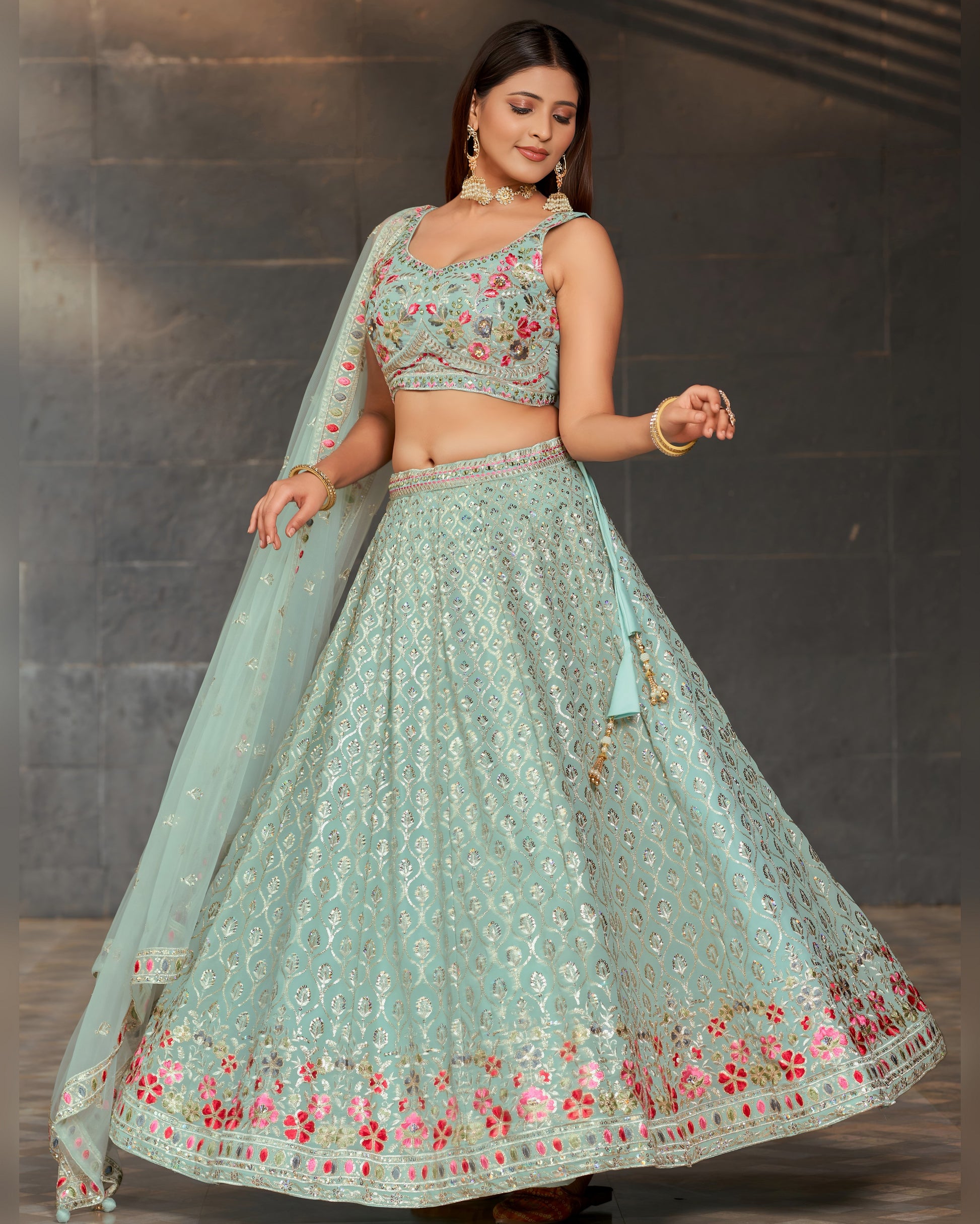 Woman wearing a light blue embroidered traditional outfit against a dark background