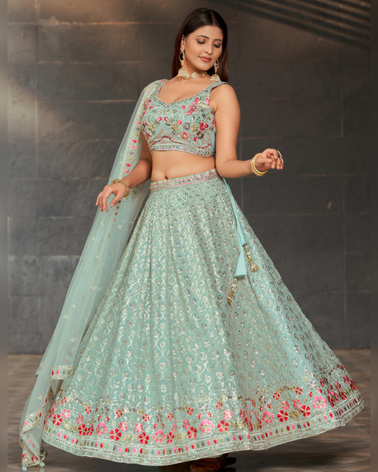 Woman wearing a light blue embroidered traditional outfit against a dark background