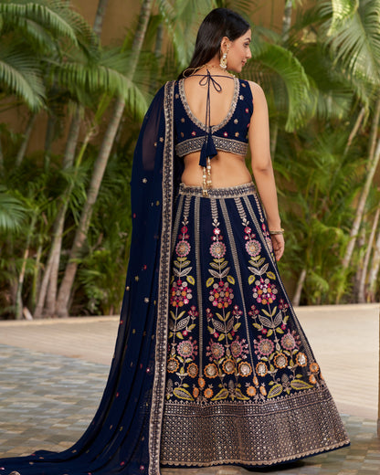 Woman wearing a navy blue embroidered lehenga with a green outdoor background