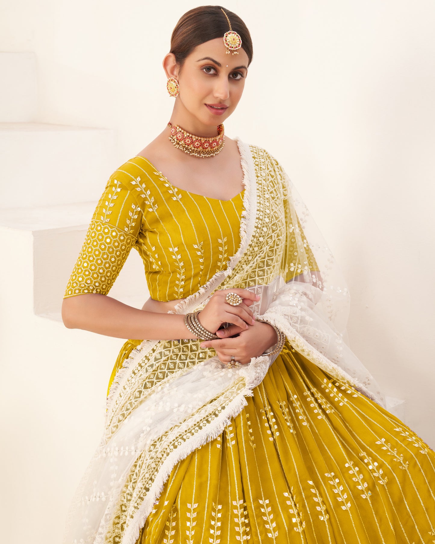 Woman wearing a yellow and white traditional outfit with jewelry on a white background