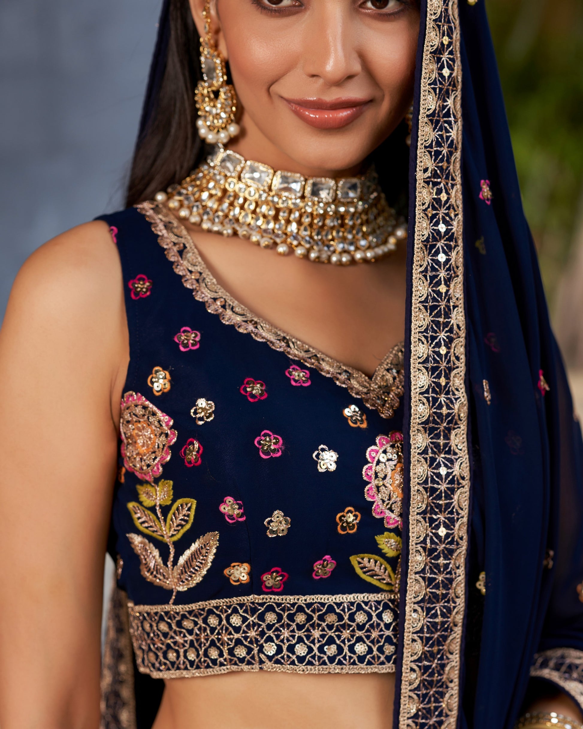 Woman wearing a navy blue embroidered blouse with gold detailing and a matching dupatta.