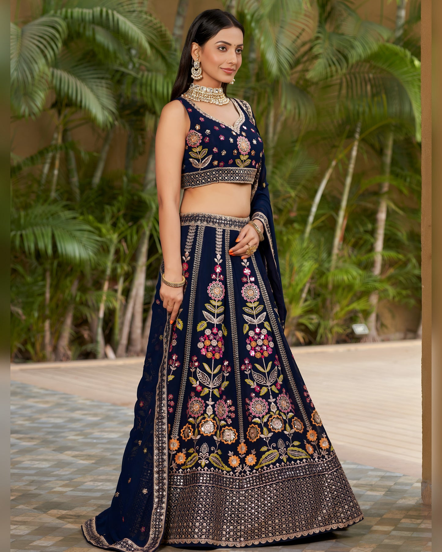 Woman wearing a navy blue embroidered traditional outfit with a green outdoor background