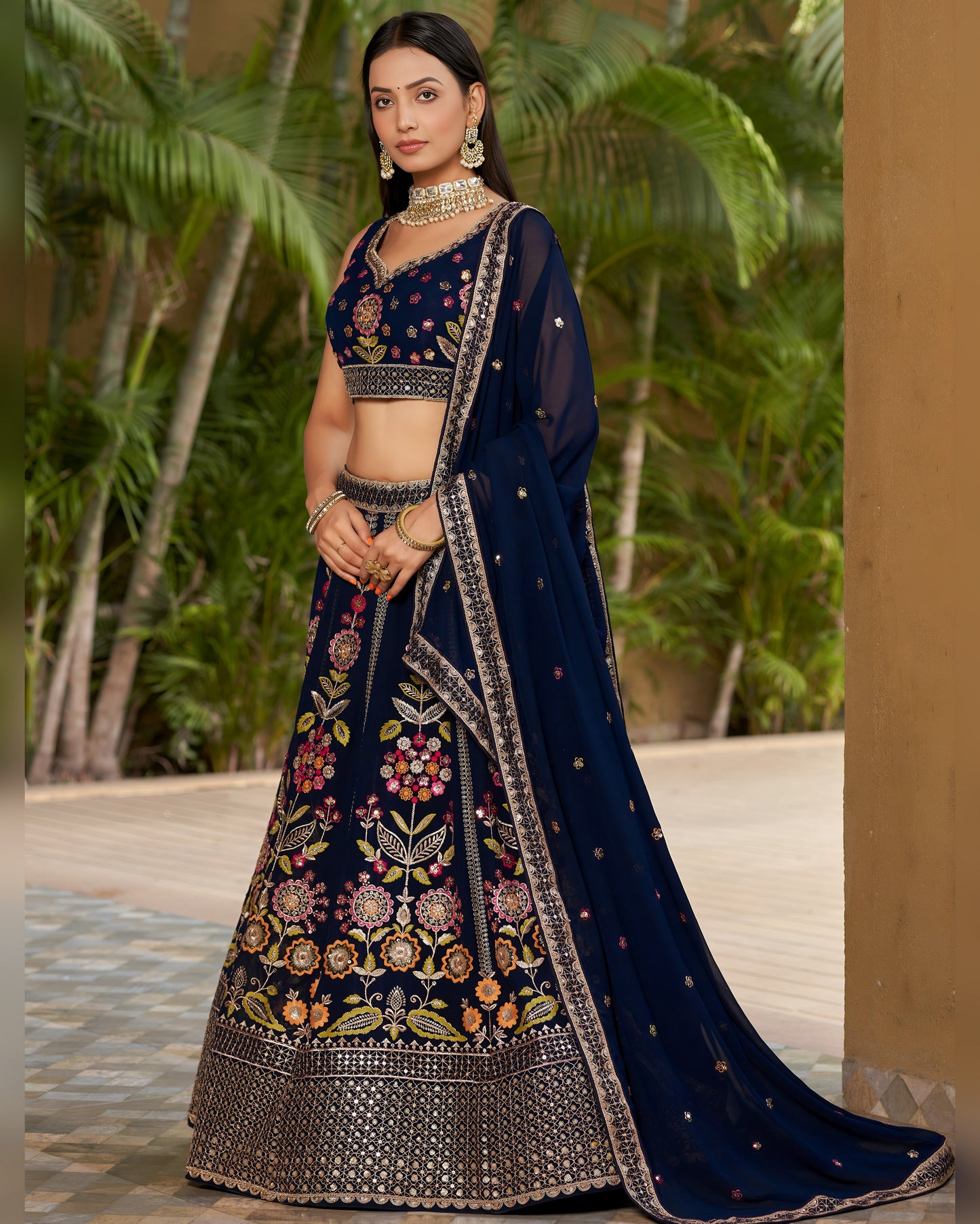 Woman in a traditional navy blue embroidered lehenga with a matching blouse, standing outdoors.