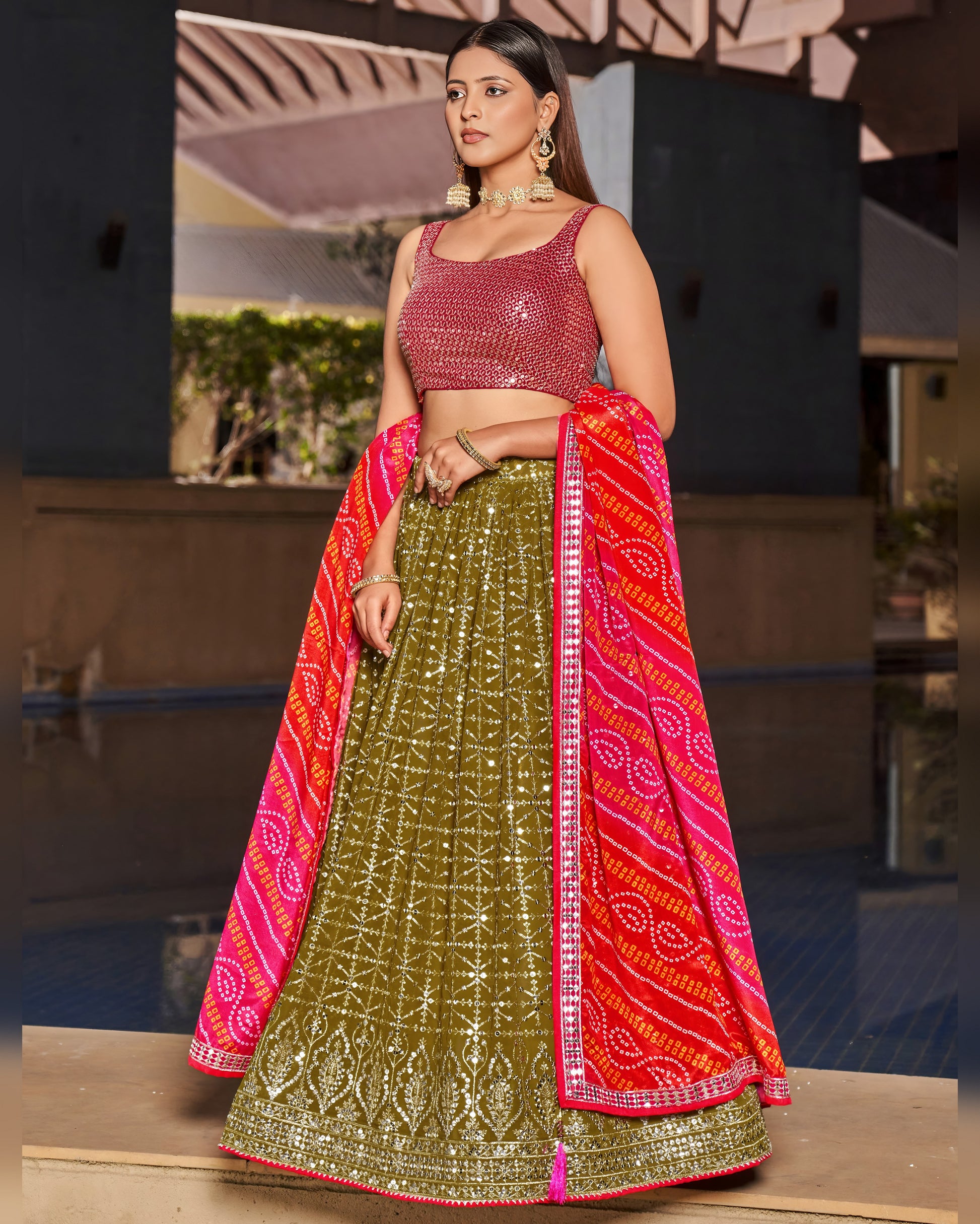 Woman wearing a traditional outfit with a green skirt and pink top, standing indoors.