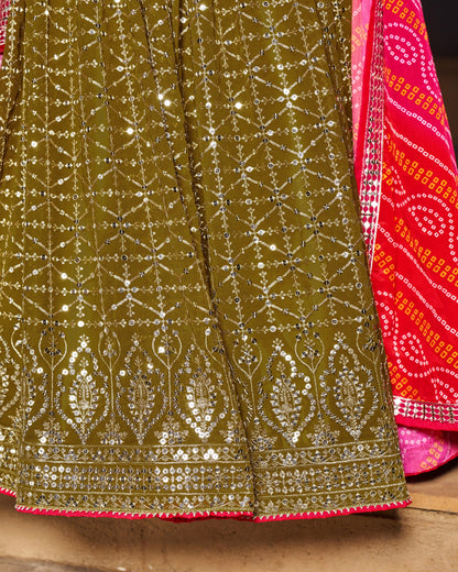 Close-up of a green embroidered fabric with silver detailing and a pink border.