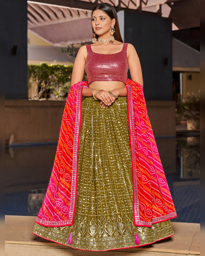 Woman wearing a traditional outfit with a pink blouse and green lehenga in an outdoor setting.