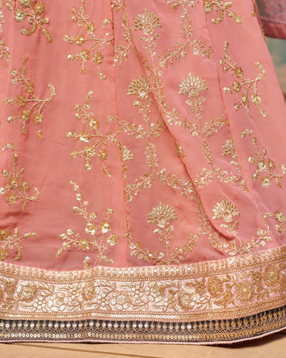 Pink fabric with gold embroidery on a wooden surface