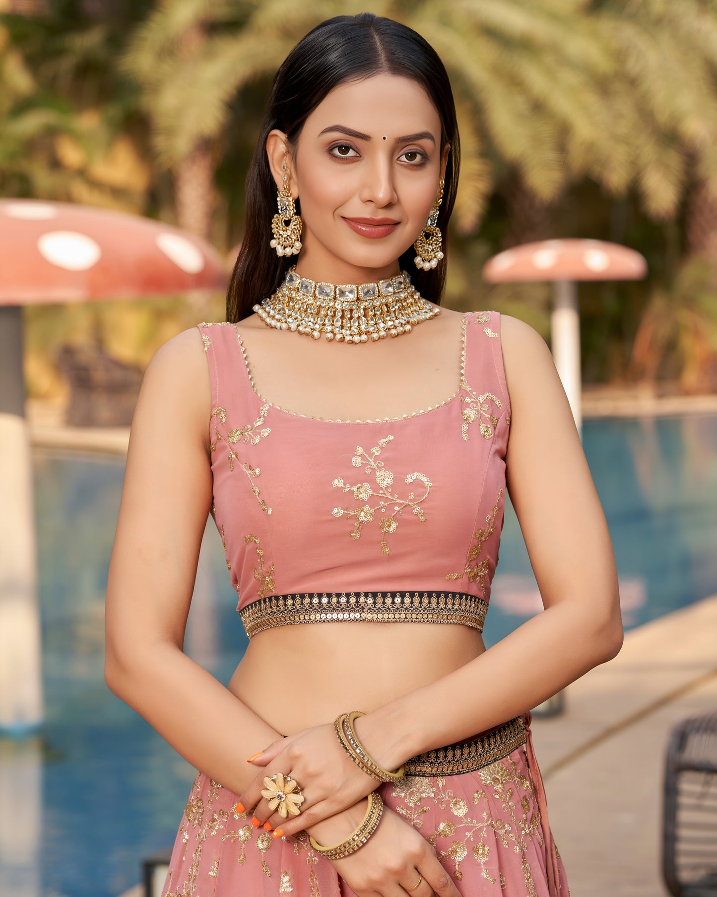 Woman in a pink traditional outfit with jewelry by a poolside