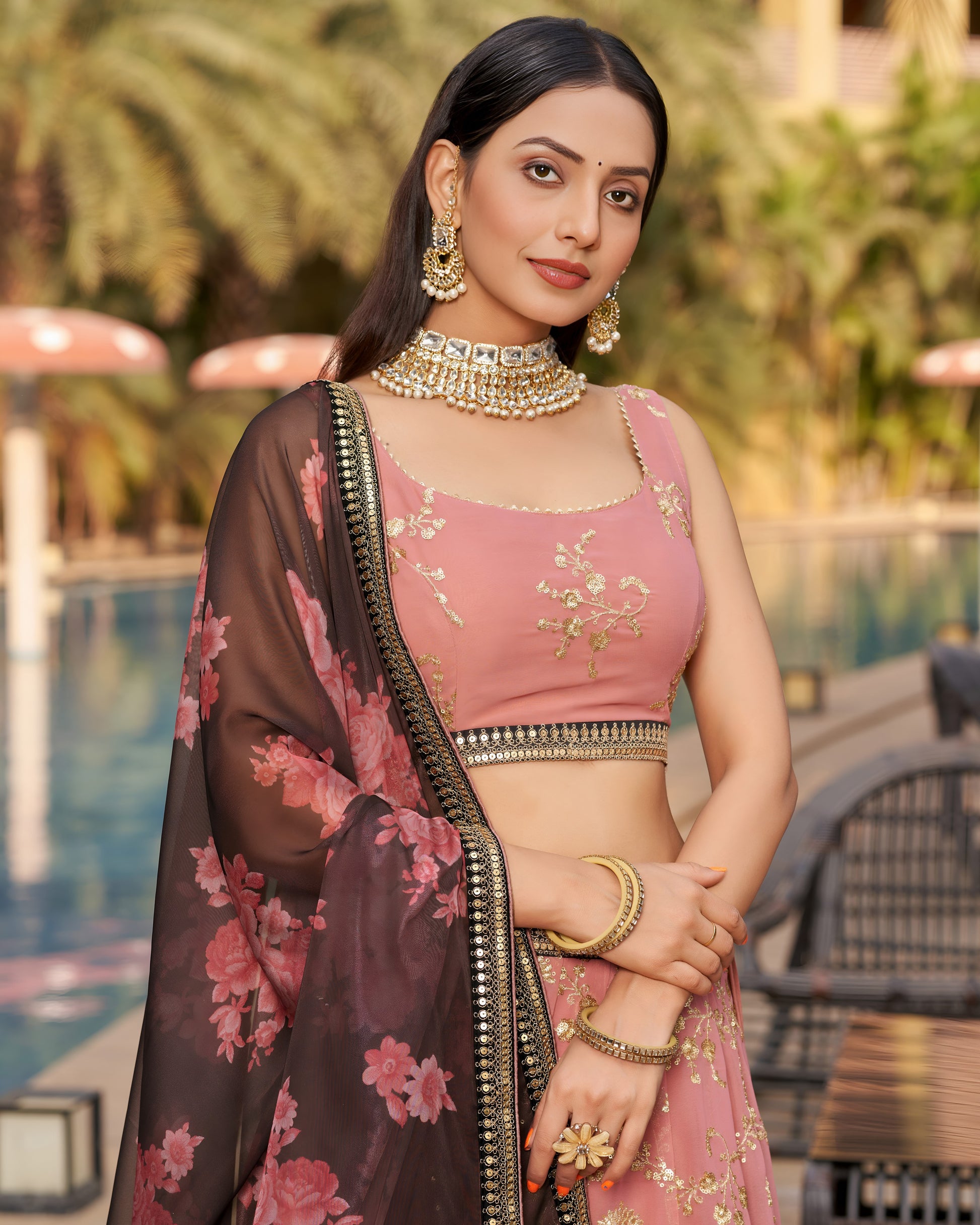 Woman in a traditional outfit with floral patterns and jewelry, standing outdoors.