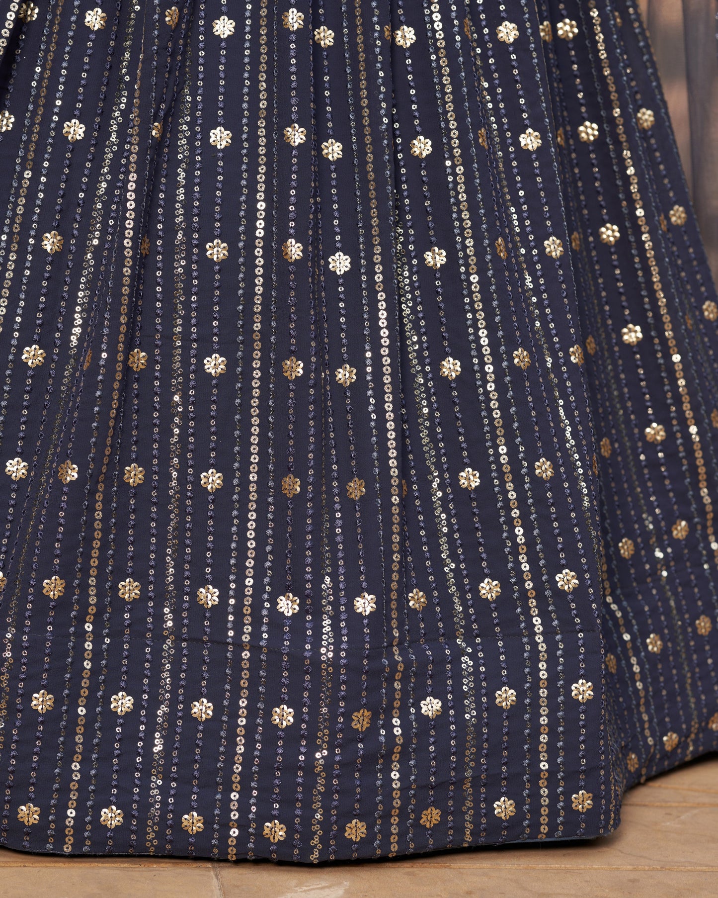 Close-up of a navy blue fabric with gold and white patterns on a wooden surface.