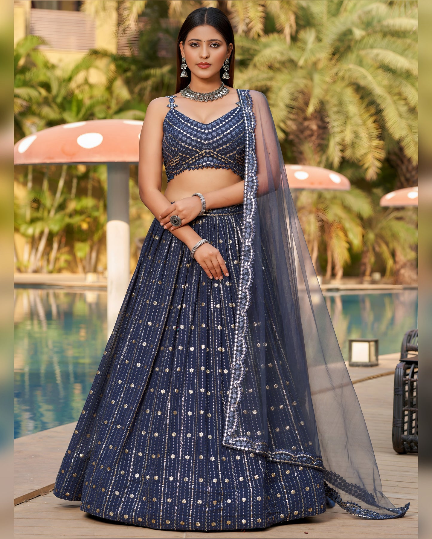 Woman in a navy blue traditional outfit with a pool and greenery in the background