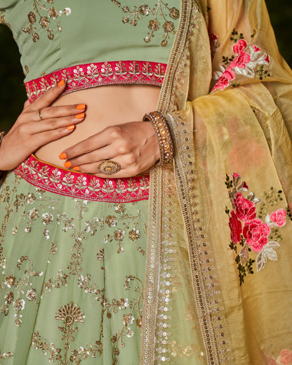 Close-up of a person wearing a traditional embroidered outfit with green, pink, and gold colors.