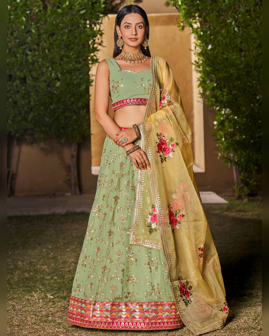 Woman wearing a traditional green and beige embroidered outfit with floral patterns.