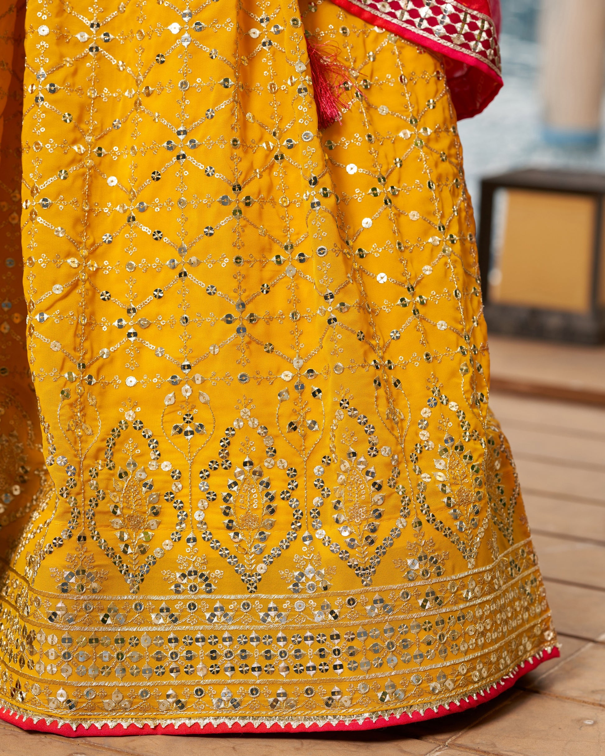 Yellow embroidered fabric with intricate patterns on a wooden surface