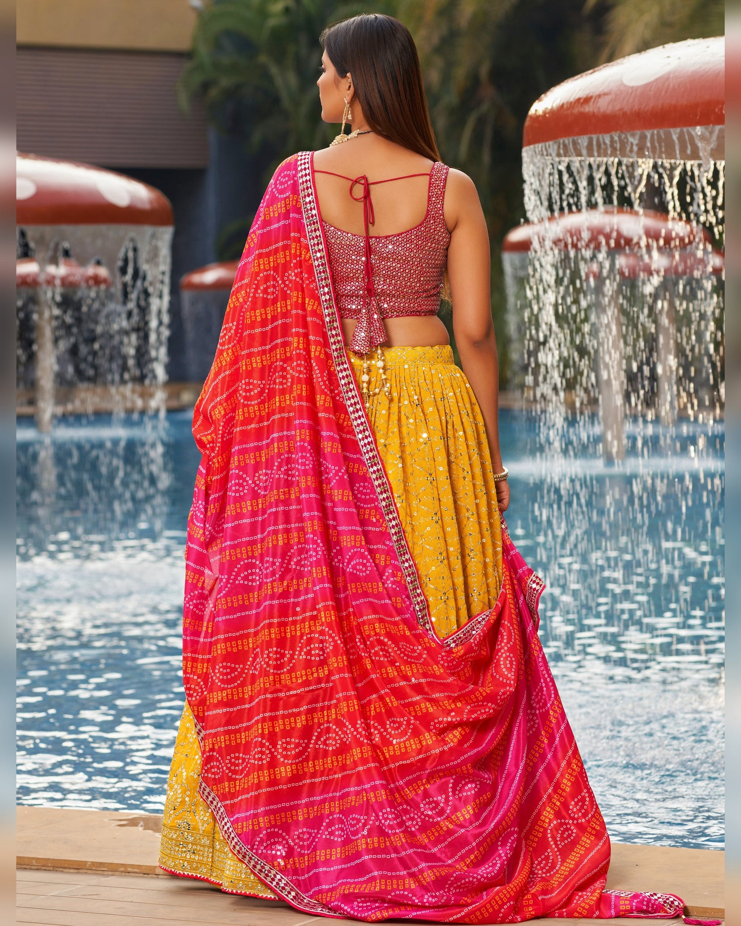 Woman in a colorful saree standing by a fountain