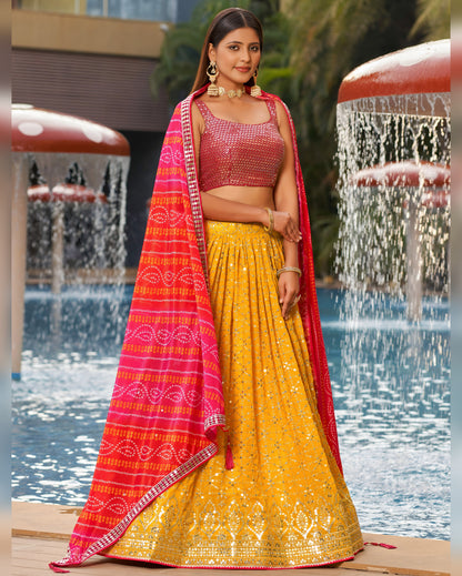 Woman in a yellow and red traditional outfit standing by a fountain.