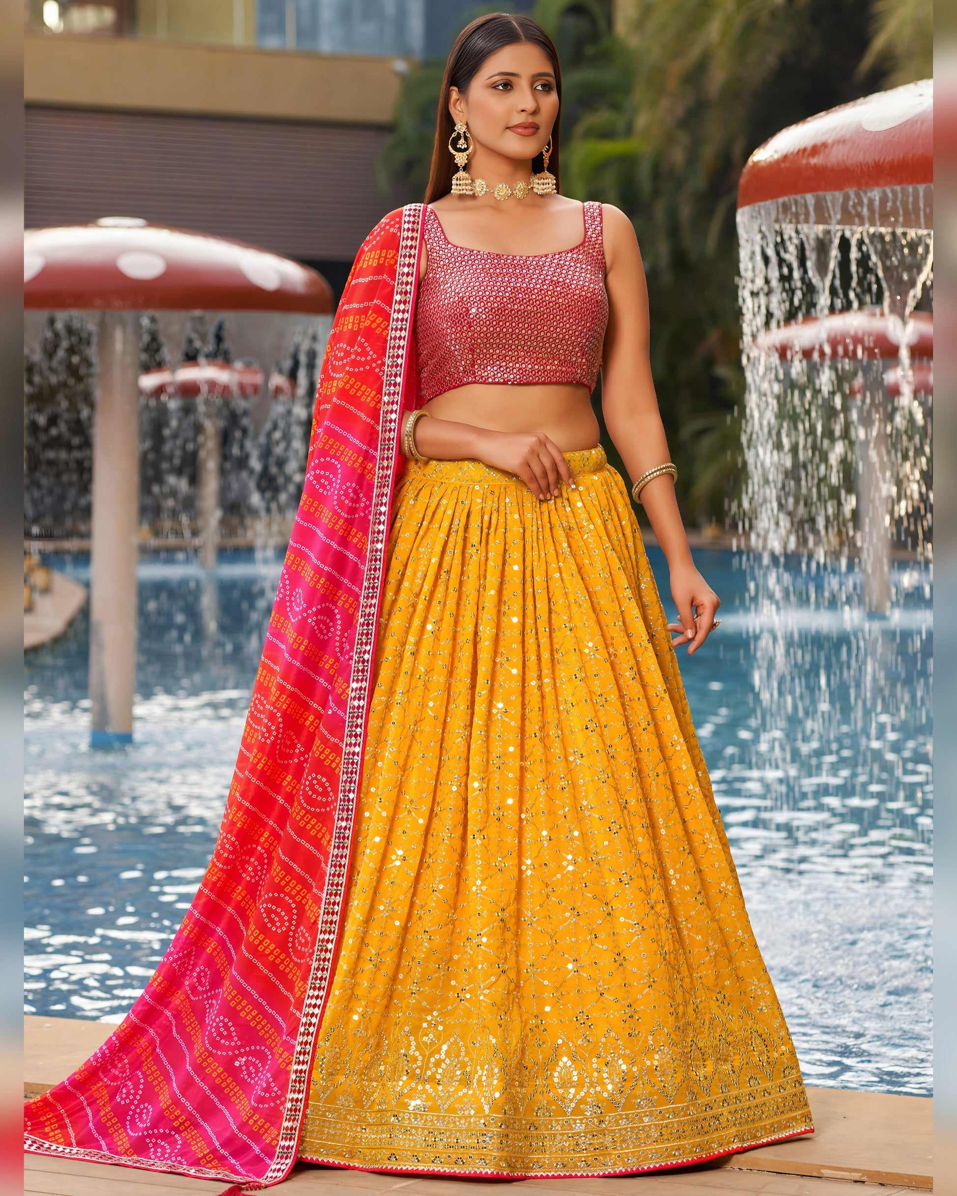 Woman in a yellow and pink traditional outfit standing by a pool.