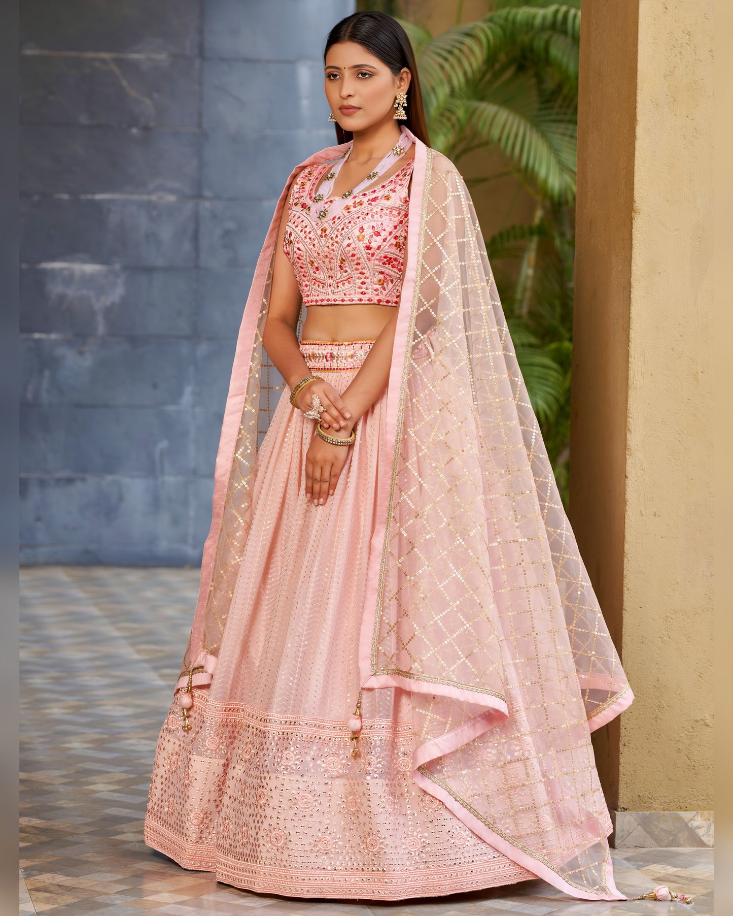 Woman wearing a pink traditional outfit with a dupatta in an outdoor setting.