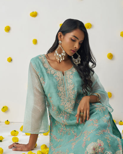 Woman in a light blue embroidered traditional outfit with yellow flowers in the background