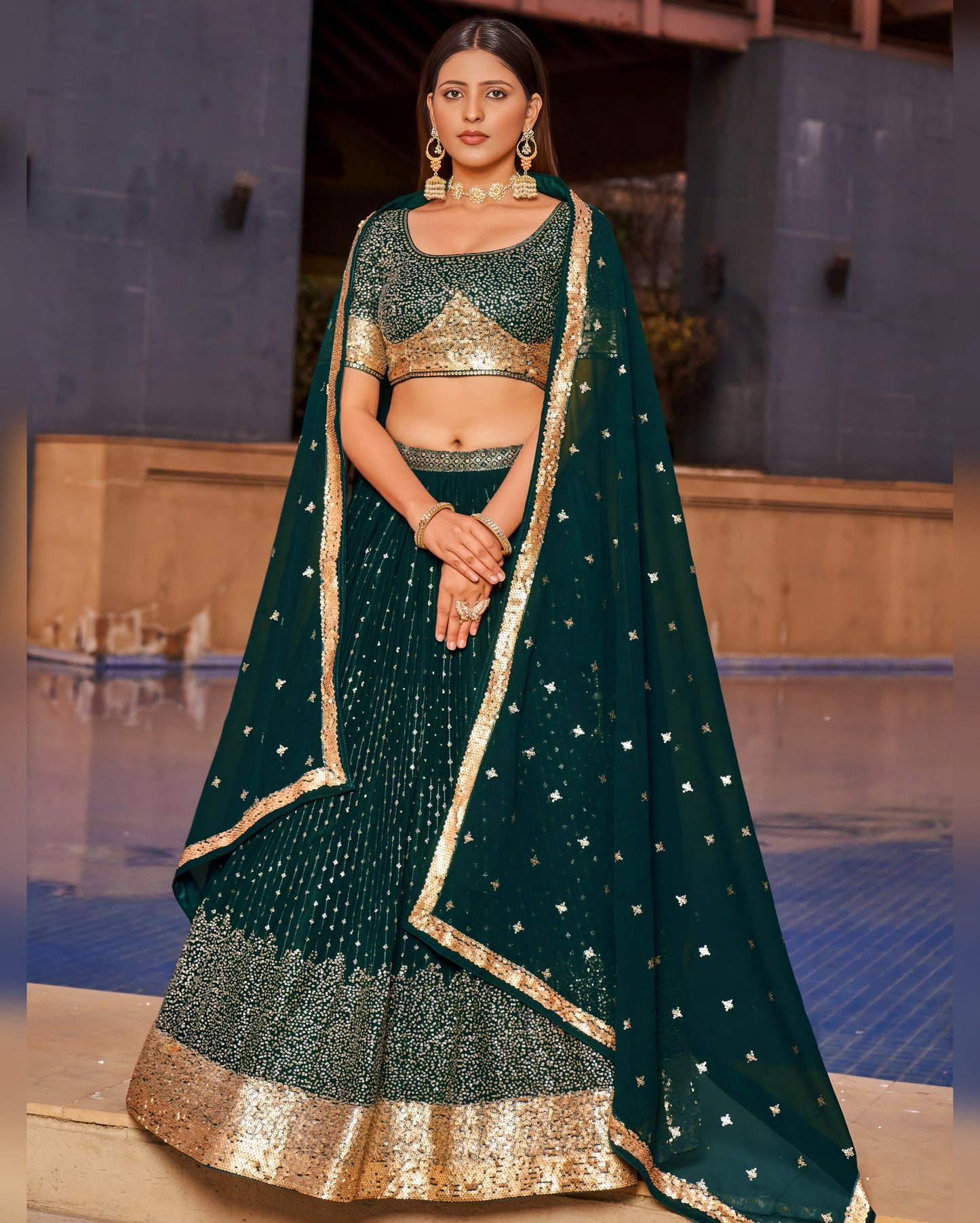 Woman wearing a green and gold traditional outfit with a pool in the background