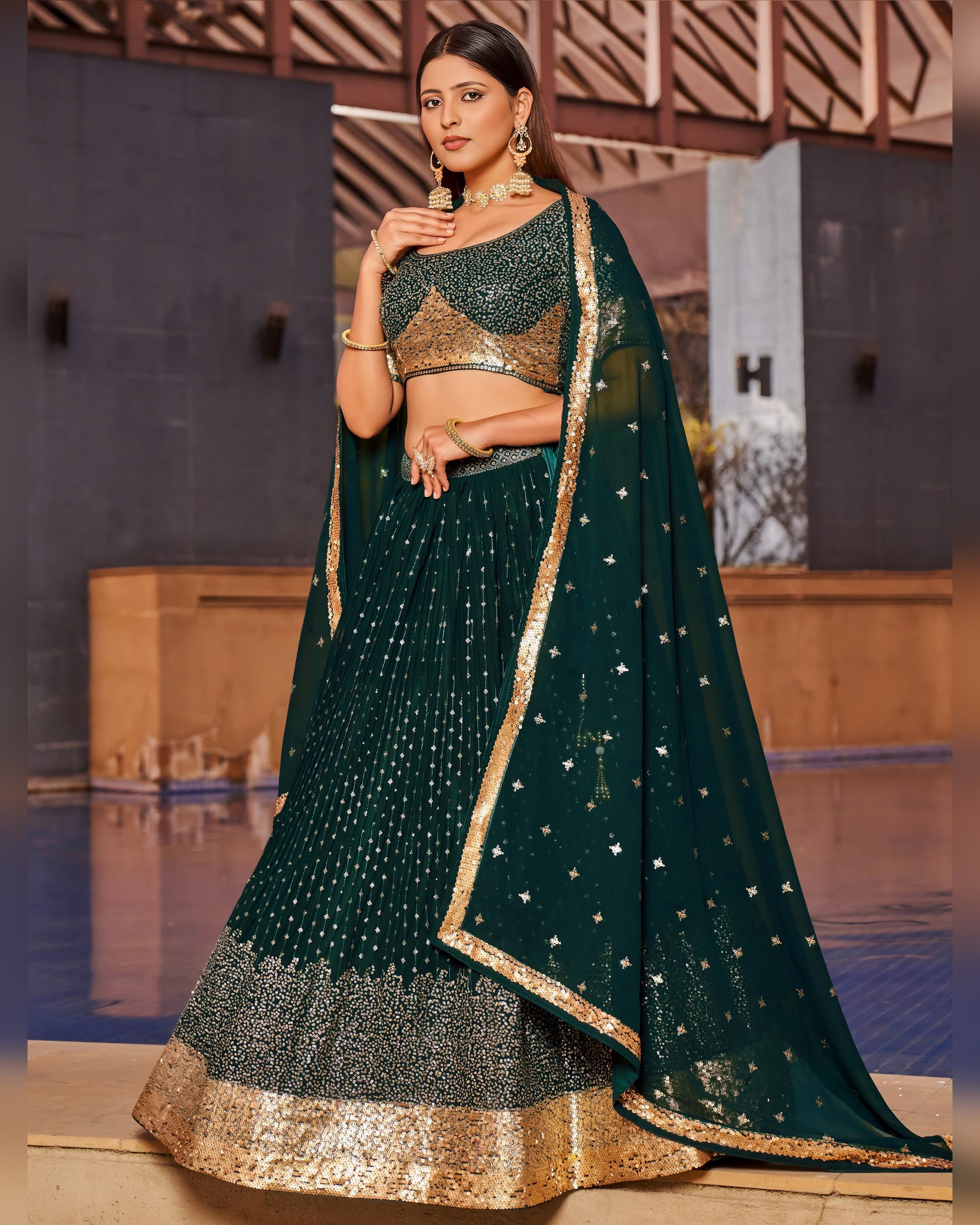 Woman wearing a dark green traditional outfit with gold accents on a stage.