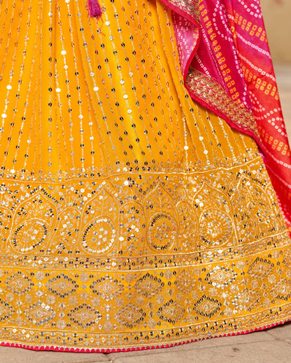 Yellow saree with intricate patterns and a pink border on a wooden surface