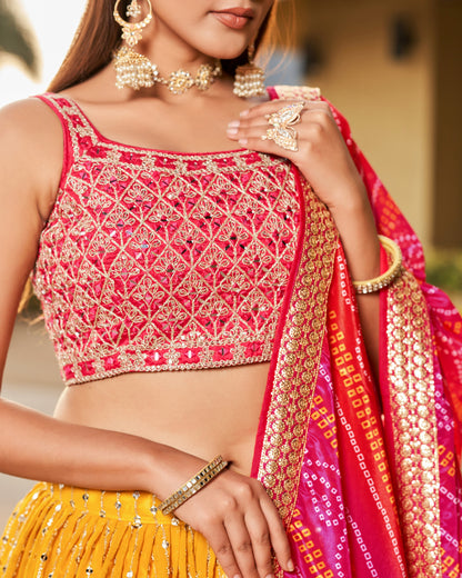 Woman wearing a traditional outfit with a pink and yellow saree and jewelry.