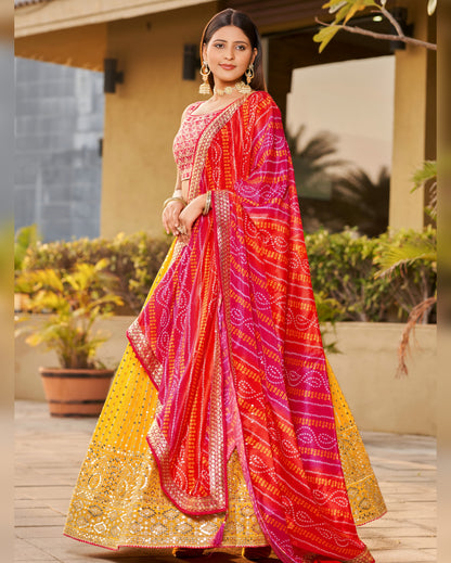 Woman wearing a vibrant red and yellow saree with a patterned border, standing outdoors.