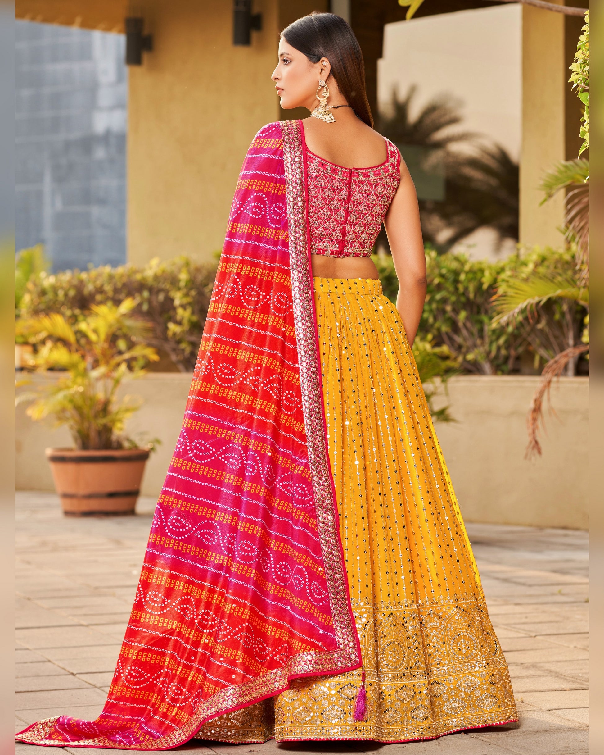 Woman wearing a traditional yellow and pink saree with a blurred outdoor background