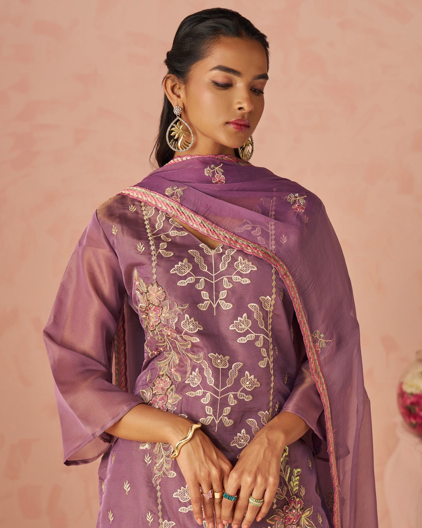 Woman wearing a purple embroidered dupatta against a pink background