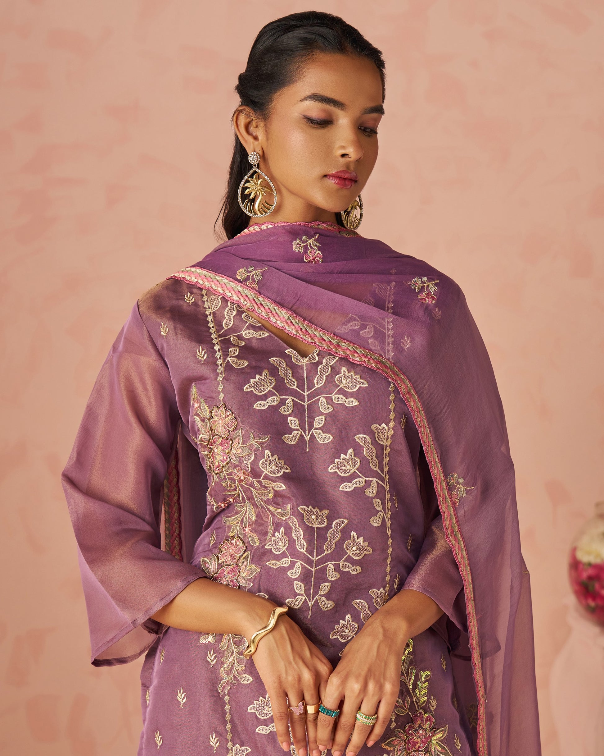 Woman wearing a purple embroidered dupatta against a pink background