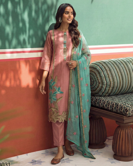 Woman in a pink and green traditional outfit standing against a colorful wall.