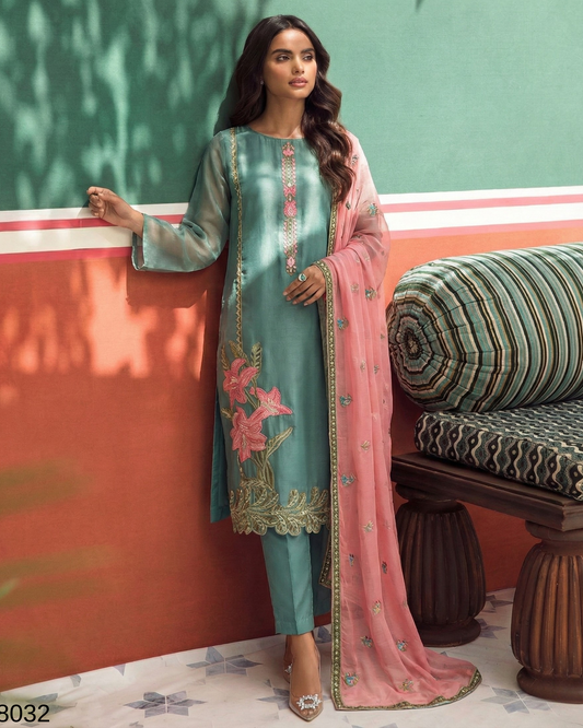 Woman in traditional outfit with teal and pink elements against a colorful wall.