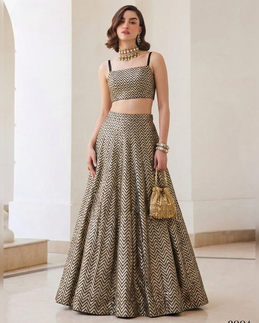 Woman wearing a patterned outfit with a long skirt and top, holding a gold handbag indoors.