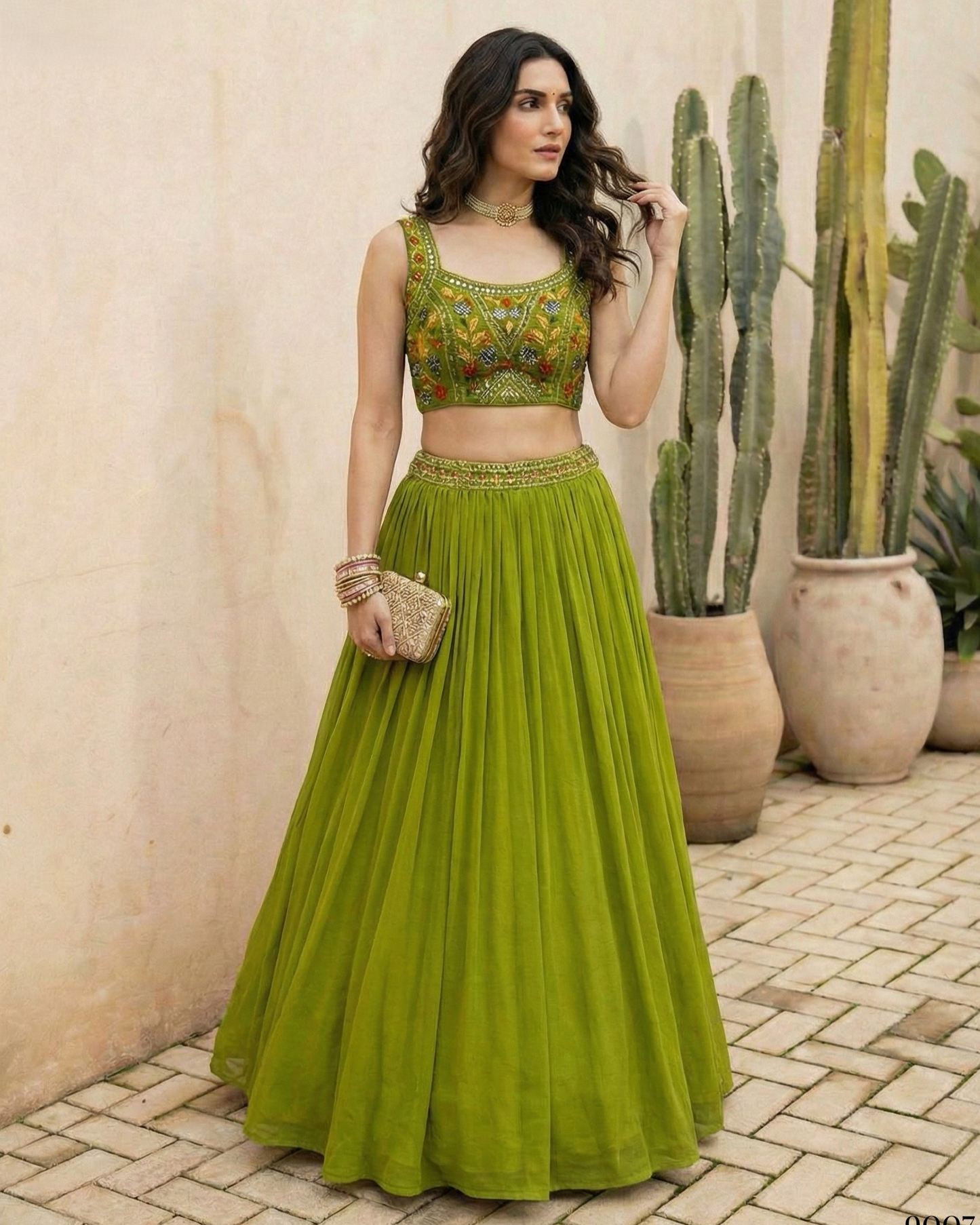 Woman in a green traditional outfit standing in front of cacti.