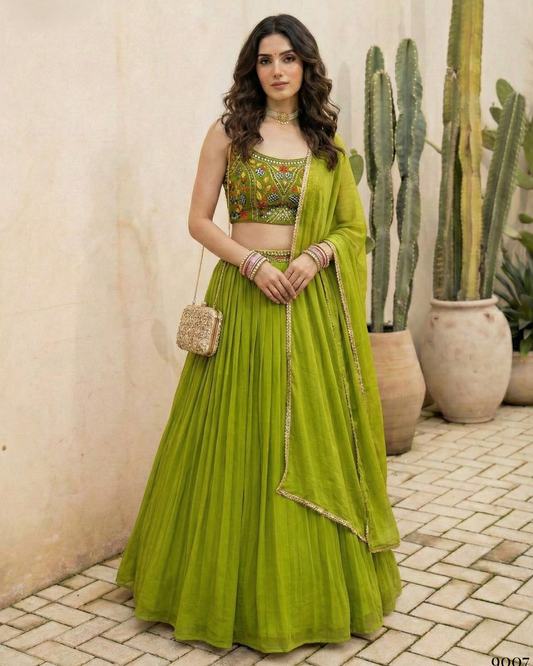 Woman in a green traditional outfit standing outdoors with plants in the background