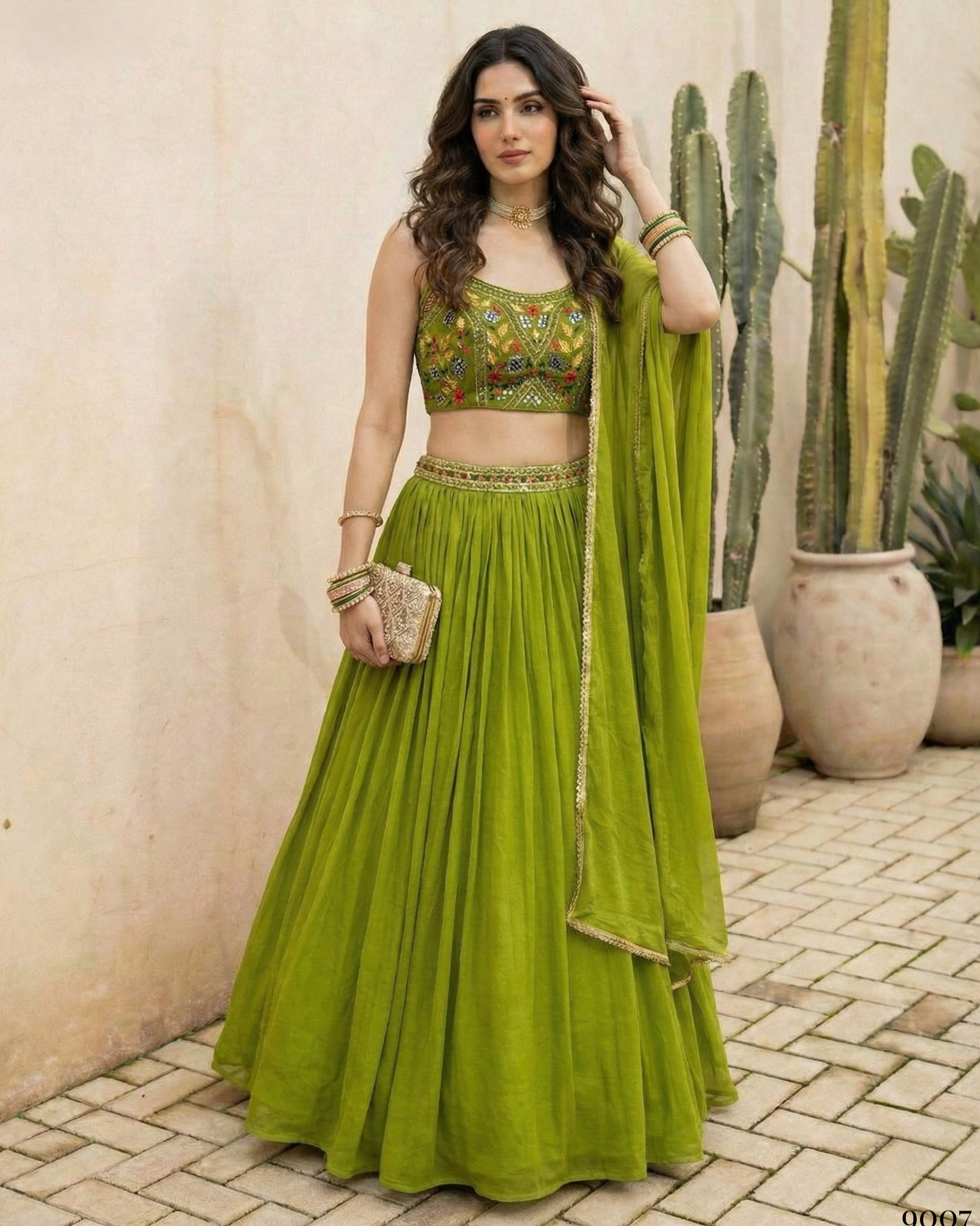 Woman in a green traditional outfit standing outdoors with cacti in the background