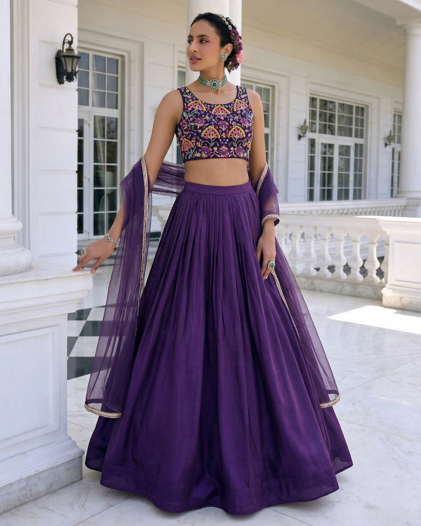 Woman in a purple traditional outfit standing in front of a white building.