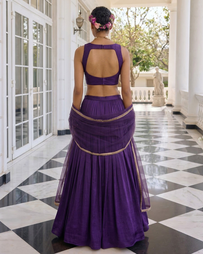 Person wearing a purple traditional outfit in a elegant indoor setting